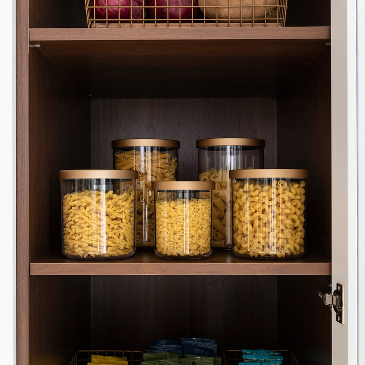 grouping of clear canisters with gold lids in pantry holding dried pasta