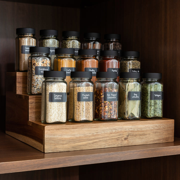 acacia wood expandable riser on kitchen shelf holding spice jars