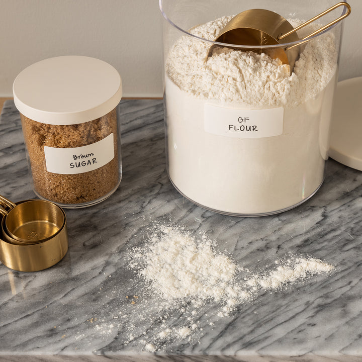 clear canisters with white lids holding baking supplies 