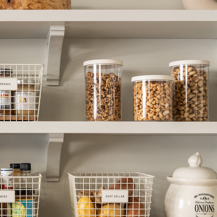 grouping of clear canisters with white lids on pantry shelf holding nuts