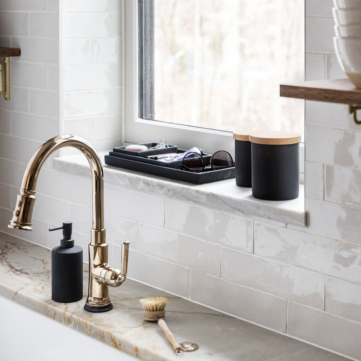 kitchen sink with black ceramic pump dispenser, black ceramic jars with wood lids and black ceramic trays organizing personal items