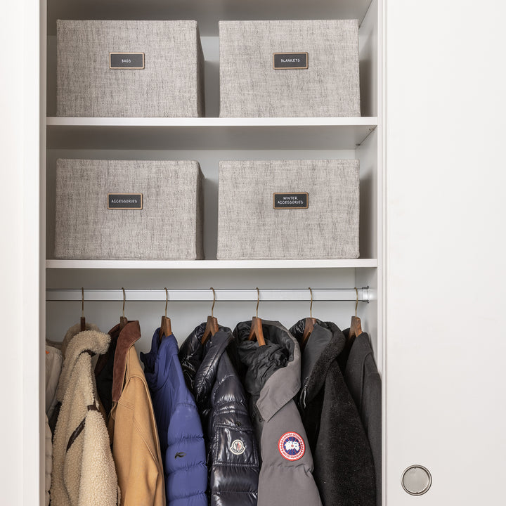 coat closet with light grey fabric bins organized with black removable pre-printed labels