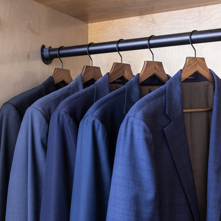 slim acacia wood hangers with black metal hook in closet holding men's suits
