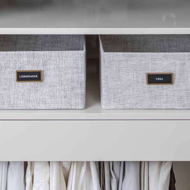 closet with light grey fabric bins organized with black removable pre-printed labels