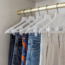 Load image into Gallery viewer, white slim hangers with black hooks holding shorts in a closet
