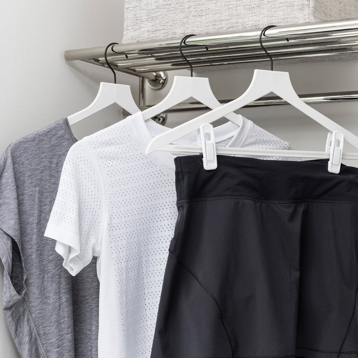 white slim, non-slip suit hangers with white hanger clips holding athletic wear in a laundry room