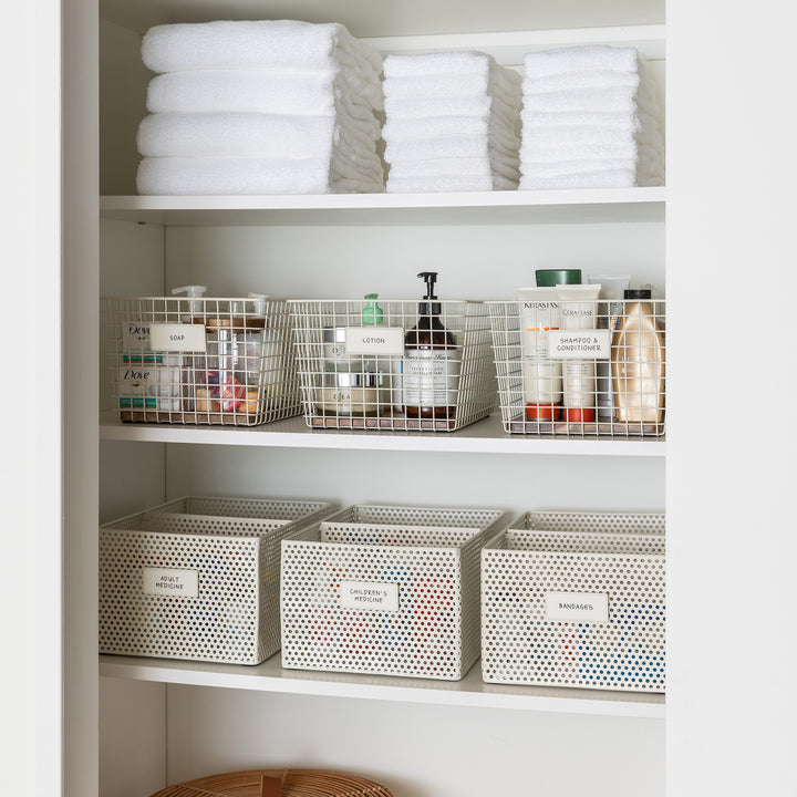 bathroom storage shelving with white metal baskets and white removable labels