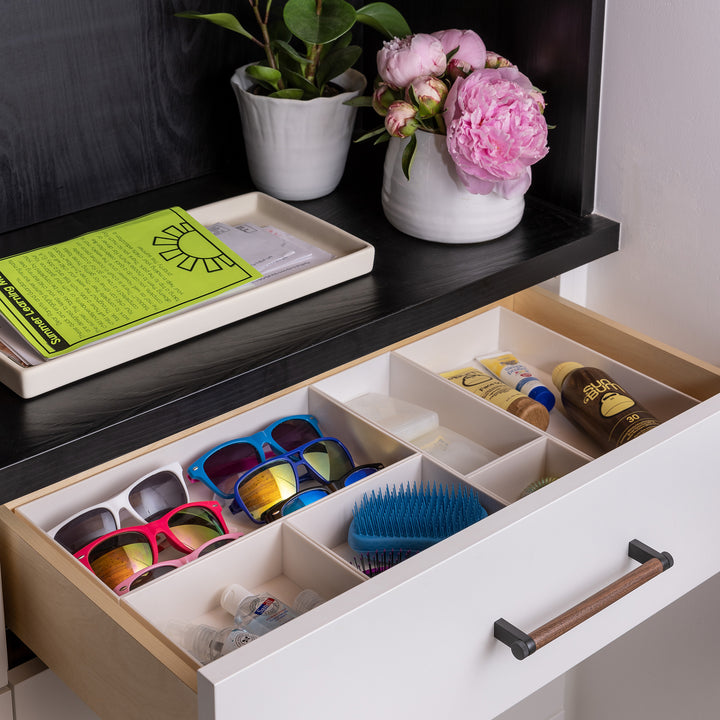 drawer with white drawer organizers holding items like sunglasses and sunscreen