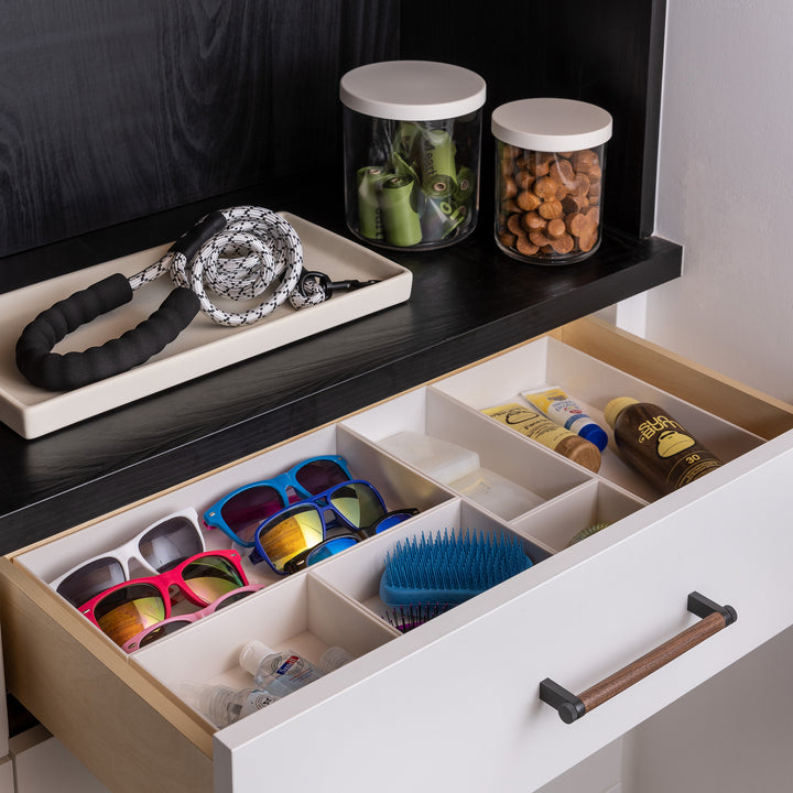drawer with white drawer organizers holding items like sunglasses, sunscreen and pet supplies